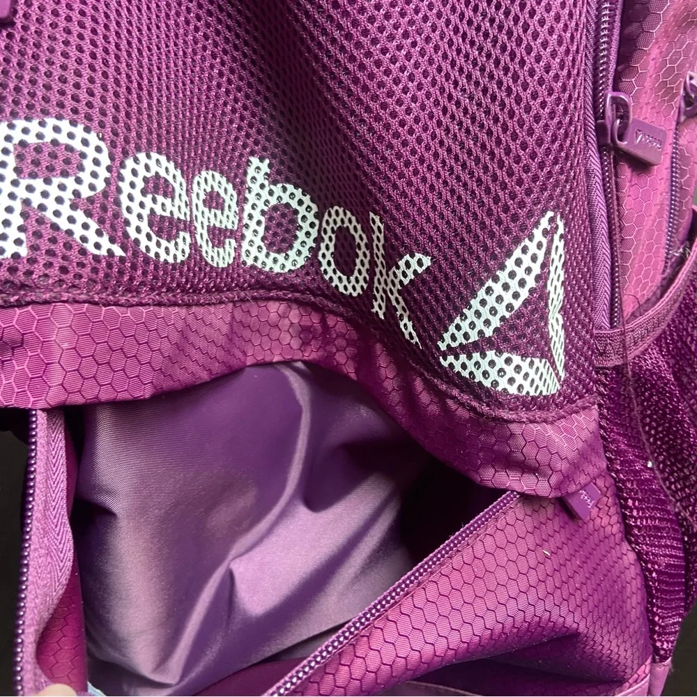 Purple Reebok book bag with tear right near strap